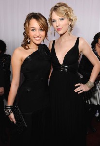 Miley Cyrus stuns in a Herve Leger by Max Azria design while Taylor Swift is stylish in a Grecian-inspired gown by Kaufman Franco. The pair sang a duet to Swift's song "15" at the Grammys.